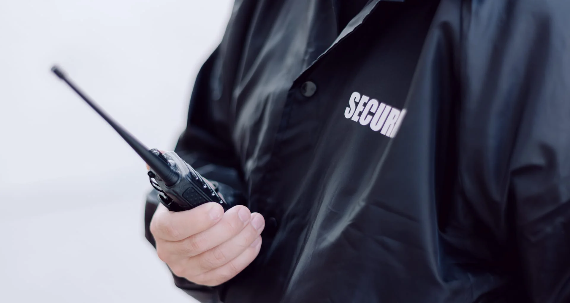 Security officer in a black jacket holding a radio